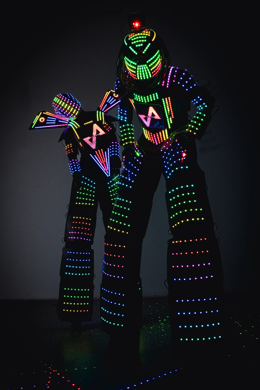 Costum robot LED EleVArts pe picioroange, cu LED-uri adresabile pe tot corpul aprinse curcubeu și ecran LED programabil în piept, luminat